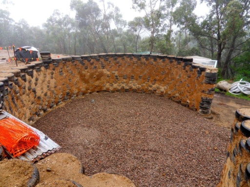Recycled tyres form a curved earth wall in the bush, illustrating our community effort to honour the land.