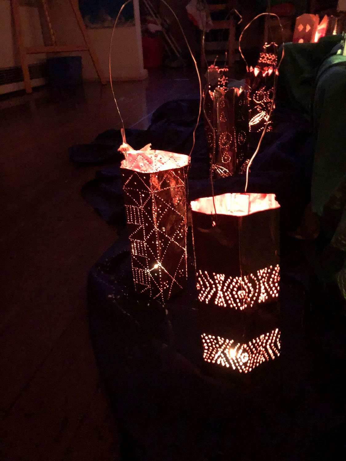 Perforated metal lanterns glow in the darkness, honouring communal connection and the magical rhythm of a winter night.