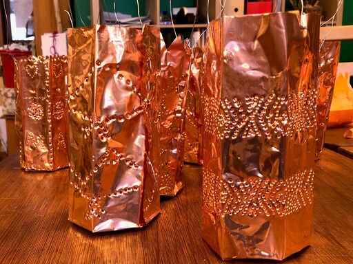 Hand-punched copper lanterns prepared for the winter walk, honouring seasonal rhythms and the shared warmth of community.