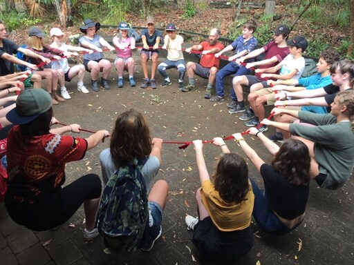 Kindlehill students holding a red rope in a unified circle, honouring their connection to the land and waterways.