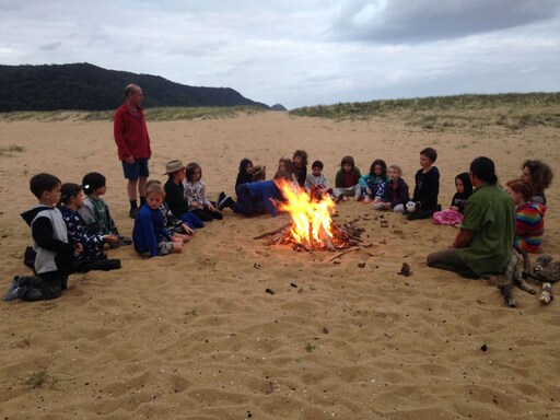 Kindlehill students sit in a communal circle around a beach campfire, honouring their connection to Country and community.