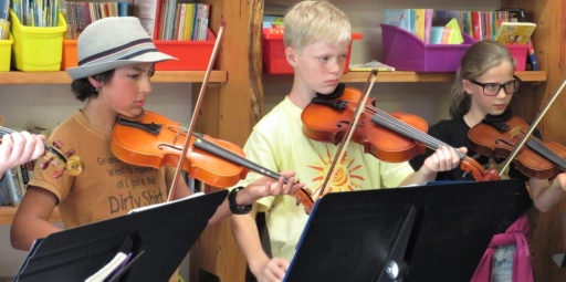 Focused students perform a string ensemble at Kindlehill, demonstrating artistic expression through creative cooperation and shared purpose.