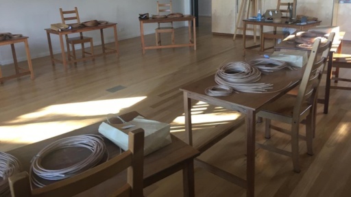 Natural cane coils rest on timber tables in a sunlit studio for a purposeful basket weaving workshop.