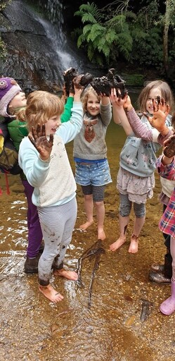 Kindlehill students at Lyrebird Dell celebrate recovering muddy shoes, illustrating cooperation and resilient connection with the wild landscape.