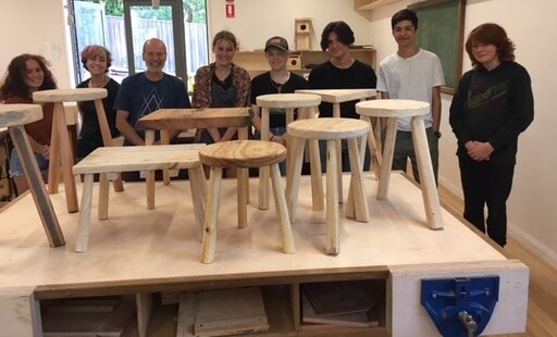 Smiling Kindlehill students showcase handcrafted repurposed timber stools, demonstrating skilful making, patience, and a shared sense of purpose.