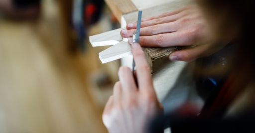 Focused hands filing metal in the workshop demonstrate the Steiner connection between head, heart, and hands through craftsmanship.