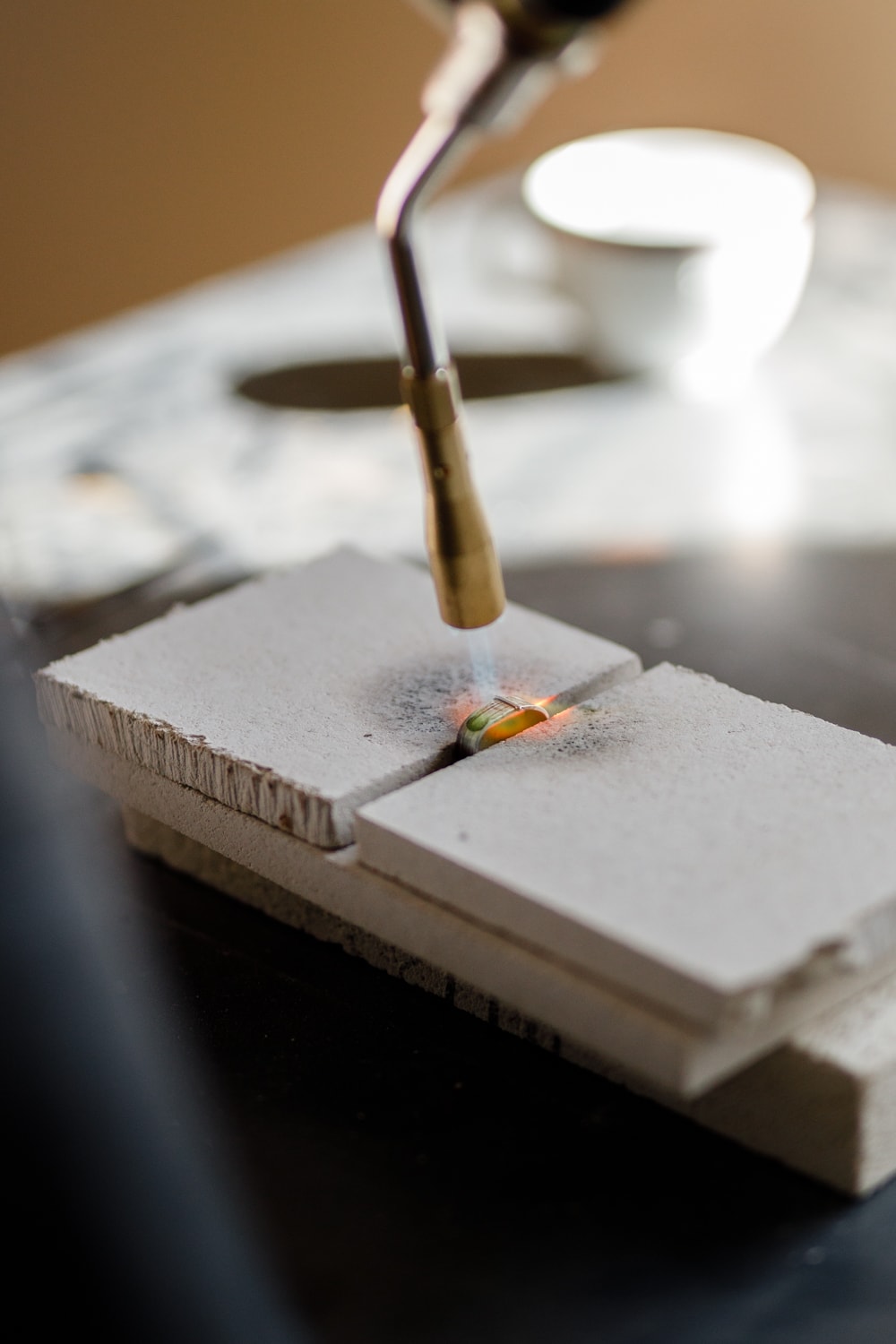 Honouring craftsmanship by soldering a silver ring, transforming materials through head, heart, and hands in the artisan workshop.