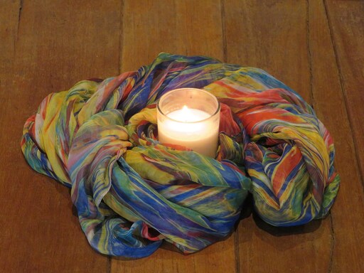 Glowing candlelight cradled in colourful silk honours the warmth, wonder, and sacred spirit of the Kindlehill classroom hearth.