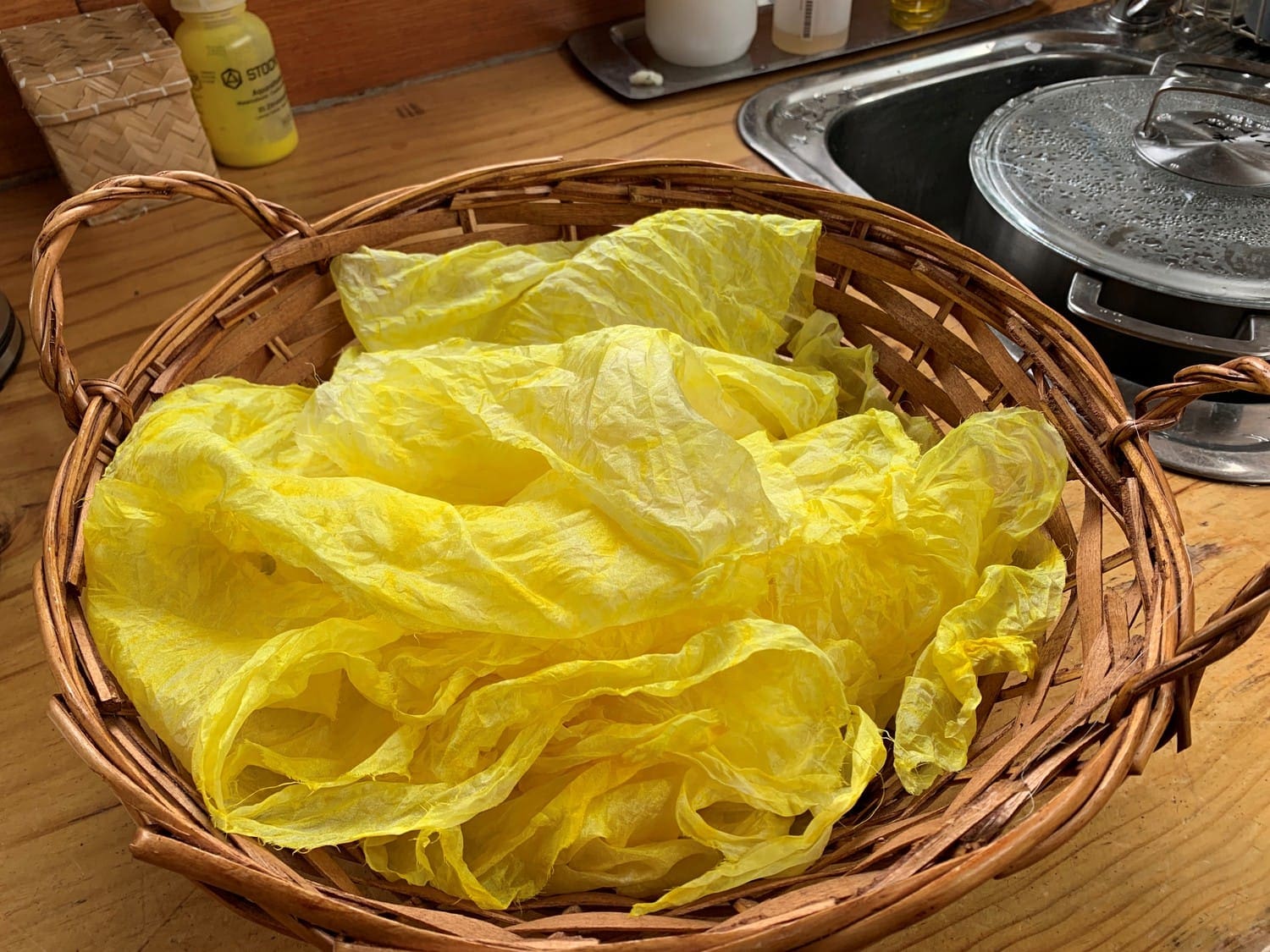Golden hand-dyed silk in a wicker basket tells ancient stories of transformation, growth, and the Sun Emperor.