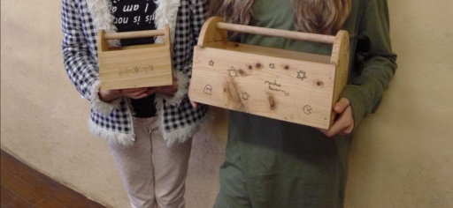 Two students proudly display hand-crafted wooden boxes, showcasing resilient craftsmanship and artistic expression through purposeful, heart-led woodwork.