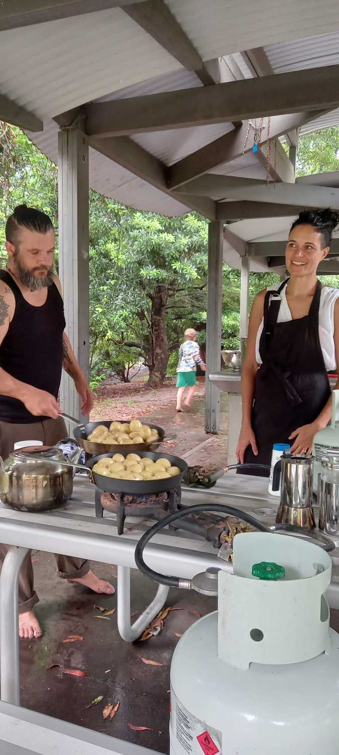 Parents prepare communal food at camp, fostering a warm spirit of community, cooperation, and shared contribution.