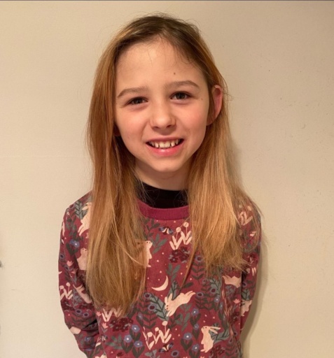 Lux joyfully wears her favourite returned jumper, celebrating a story of community care and kindness at Kindlehill.