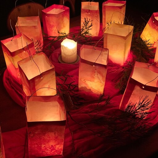 Glowing paper lanterns surround a central candle, symbolising shared light and community connection during the Winter Night celebration.