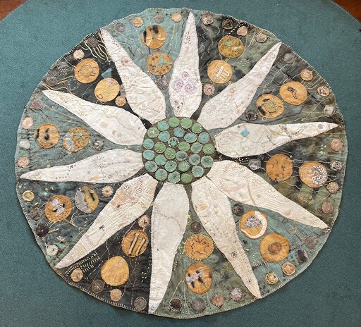 Hand-stitched circular talking rug featuring a flannel flower centre, symbolising community recovery, resilience, and connection to Country.