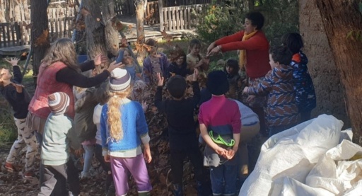Kindlehill students and teachers toss autumn leaves together, celebrating seasonal rhythms and the spirit of community collaboration.