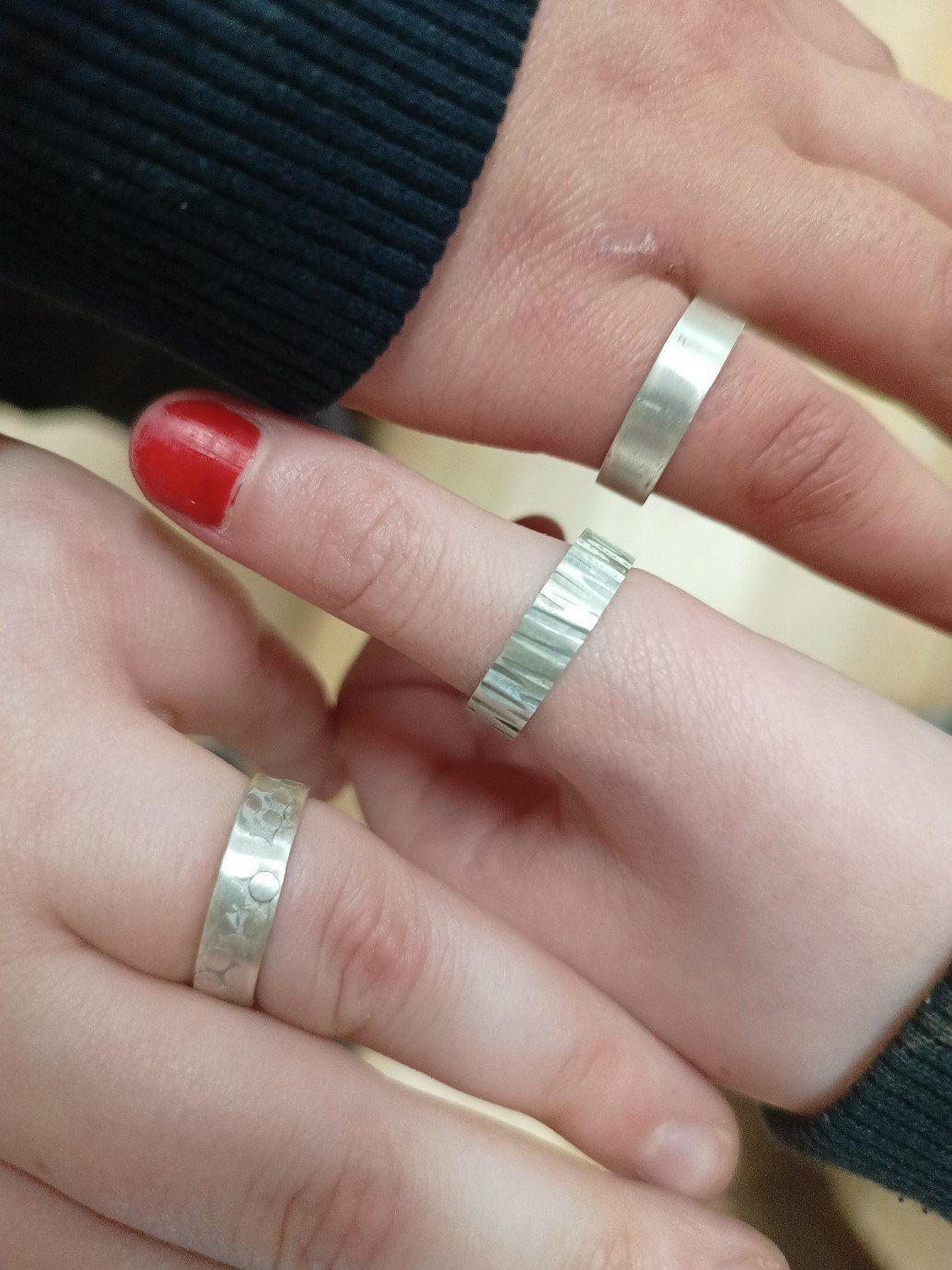 Three Kindlehill students wear hand-hammered sterling silver rings, displaying nature-inspired textures and honouring their artistic craftsmanship and connection.
