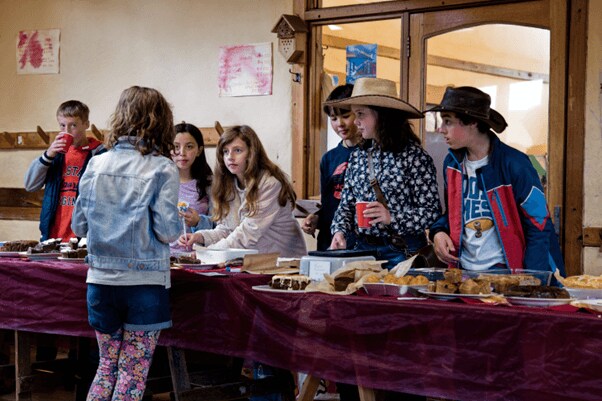 Kindlehill students cooperate at a community event, demonstrating social responsibility and building the village through shared contribution.
