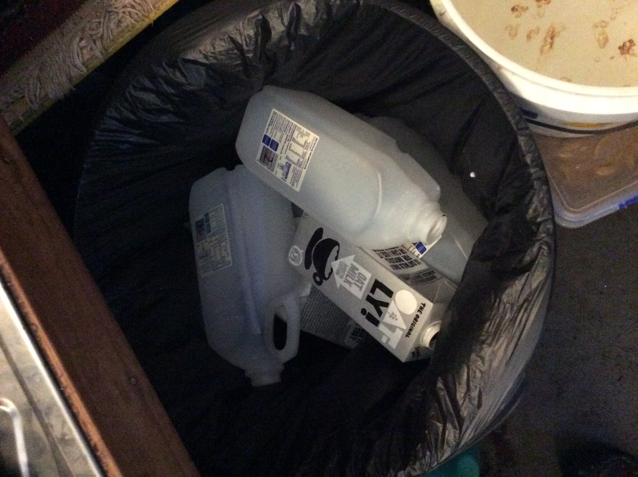 Discarded plastic cartons fill a bin, illustrating the environmental waste Kindlehill students replace with sustainable bulk systems.