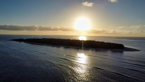 Golden sun sets over a remote coral island, reflecting a journey of resilience and earth-centred learning through nature.
