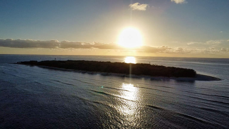 Golden sun sets over a remote coral island, reflecting a journey of resilience and earth-centred learning through nature.