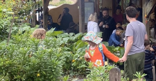 Families connect in the Kindlehill garden, sharing snacks and building a warm, inclusive community village.