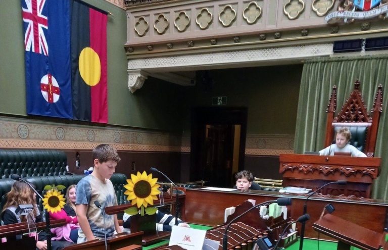 Kindlehill students role-play democratic debate in NSW Parliament, honouring history and social justice under the Aboriginal flag.