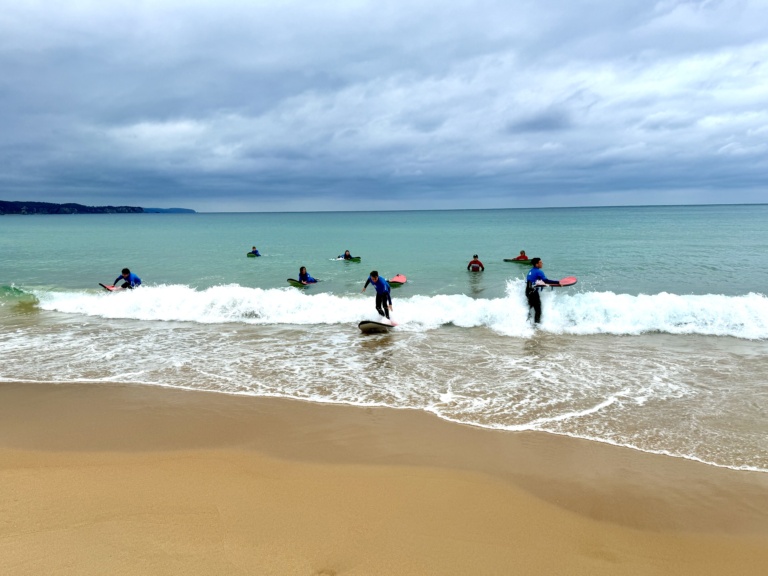 Kindlehill students surfing Pacific waves, honouring Country and building resilience through joyful shared experiences in the natural world.