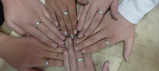 Student hands wearing handmade silver rings unite in a circle, symbolising the fusion of creative craftsmanship and community connection.