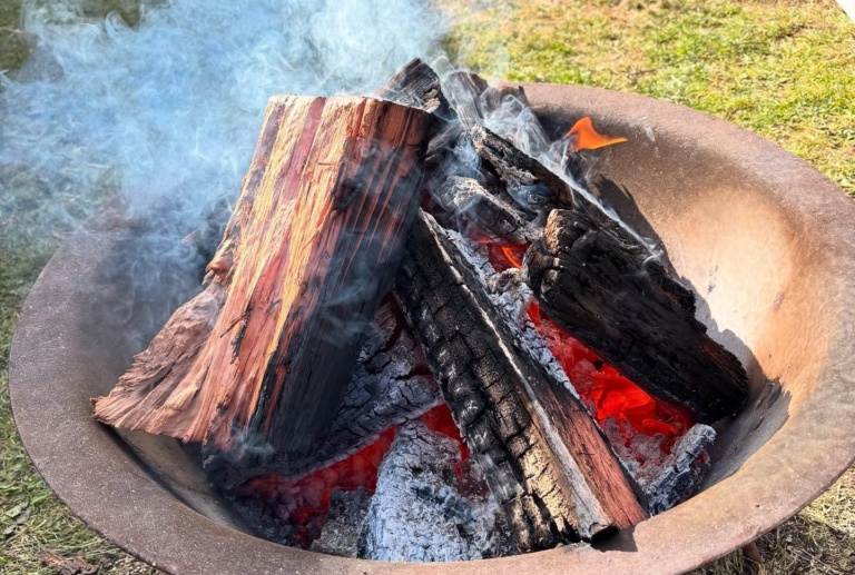 Smoke rises during a sacred smoking ceremony, honouring Country and weaving together the warm spirit of our community village.