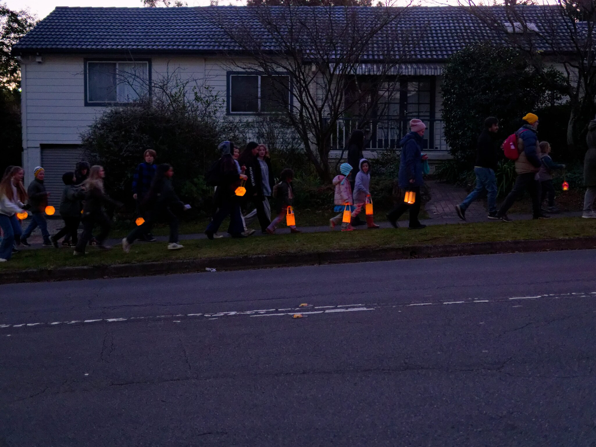 Children and families carry glowing lanterns through the winter dusk, sharing a communal ritual of hope and light.