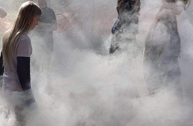 Students stand amidst morning mist and ceremonial smoke while honouring Country during a winter solstice gathering.