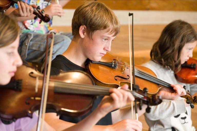 Focused students express head, heart, and hands through collaborative musical performance within the string ensemble.