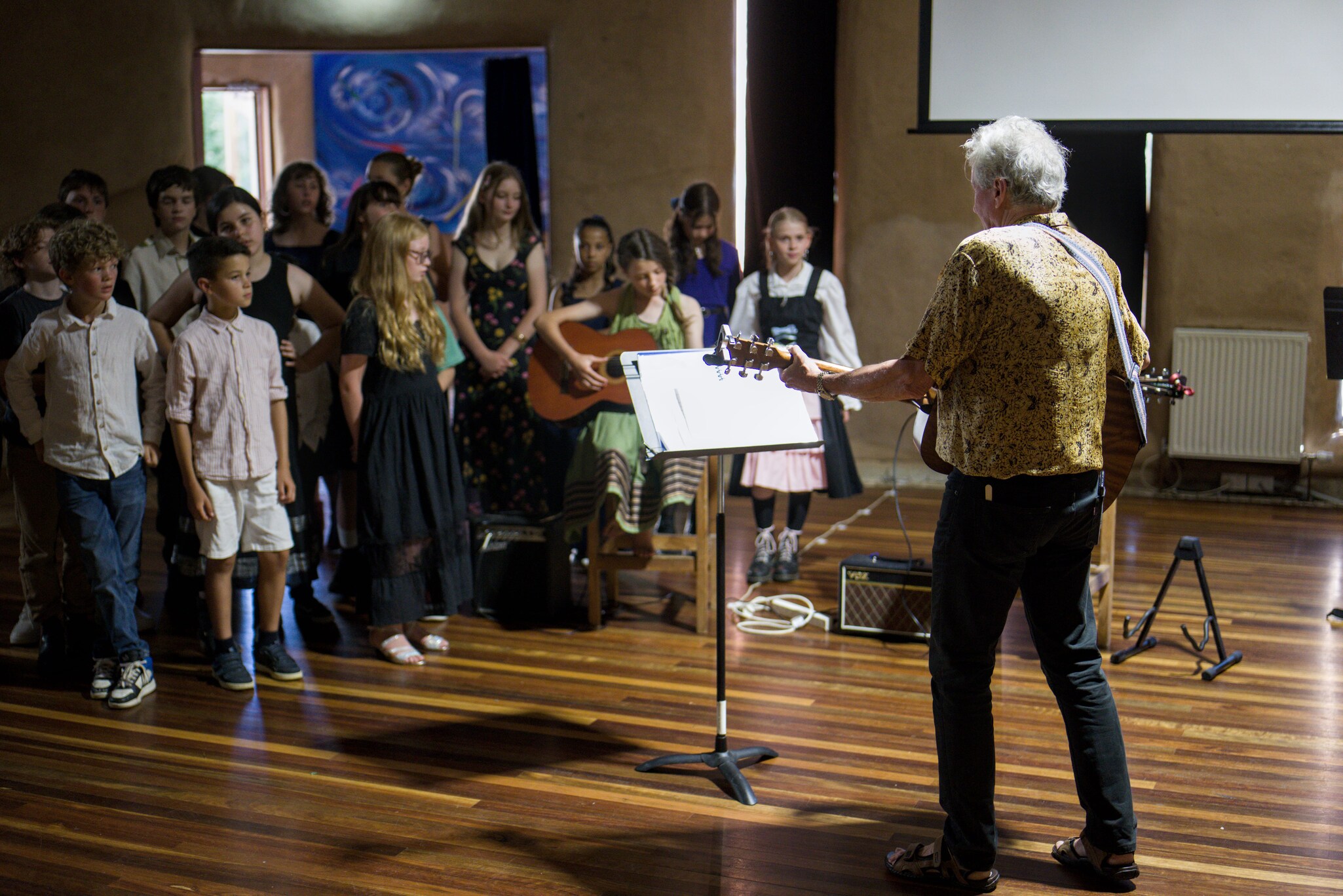 Students and John Daniel unite in song, honouring community milestones through shared musical expression and celebratory performance.