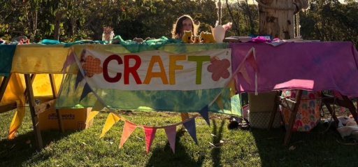 A child presents handmade keepsakes at a vibrant stall, celebrating creative contribution and the warm spirit of community.
