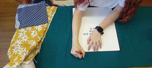 A Kindlehill student meticulously marks fabric for satchels, transforming upcycled textiles into meaningful handcrafted creations through purposeful work.