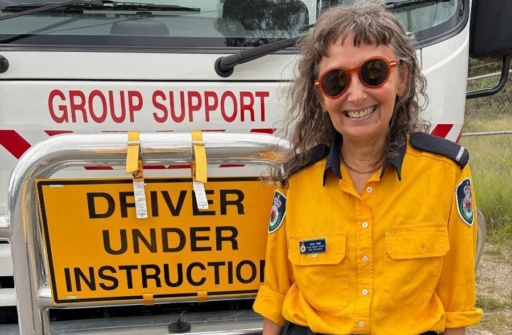 Libby Gahl wears a Rural Fire Service uniform before a community support truck, demonstrating her commitment to service.