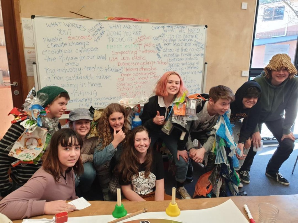 Empowered students wearing recycled materials demonstrate earth-centred social responsibility through creative action and environmental advocacy.