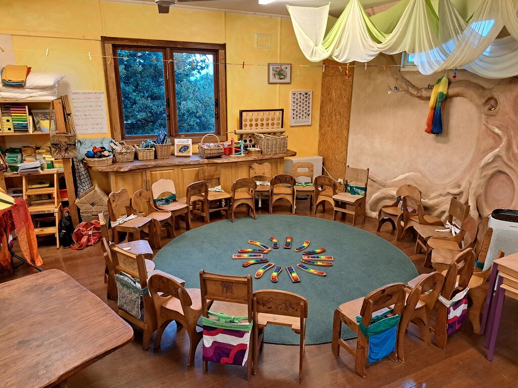 Wooden chairs form a welcoming circle, honouring community connection and the rhythmic heart of the Kindlehill classroom village.