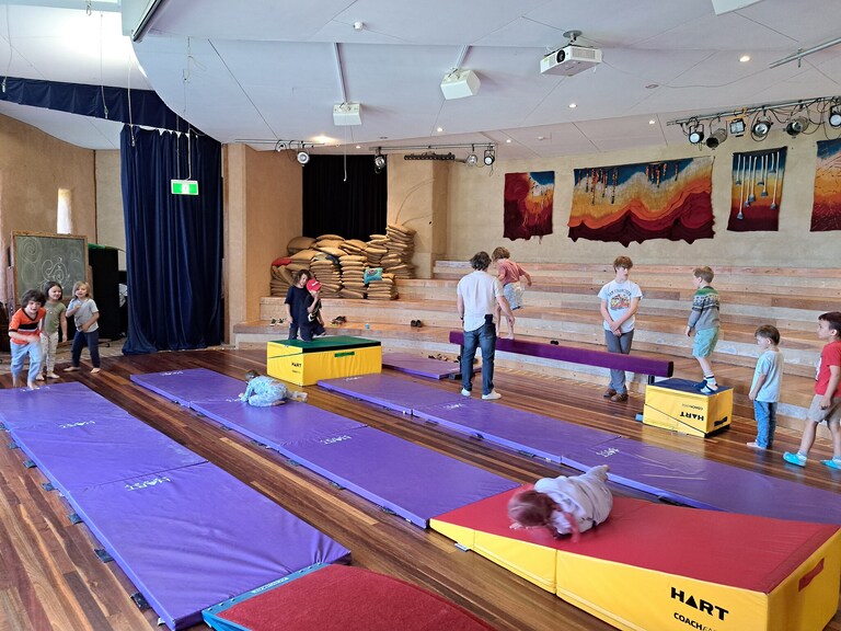 Children develop physical resilience and inner strength through joyful movement and balance within their art-filled community hall.