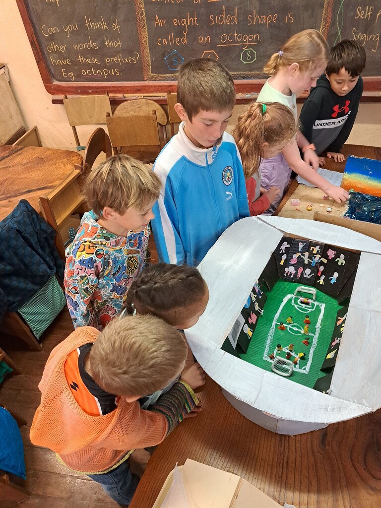 Children collaborate on a hand-crafted stadium, weaving imagination and community into a shared artistic journey at Kindlehill.