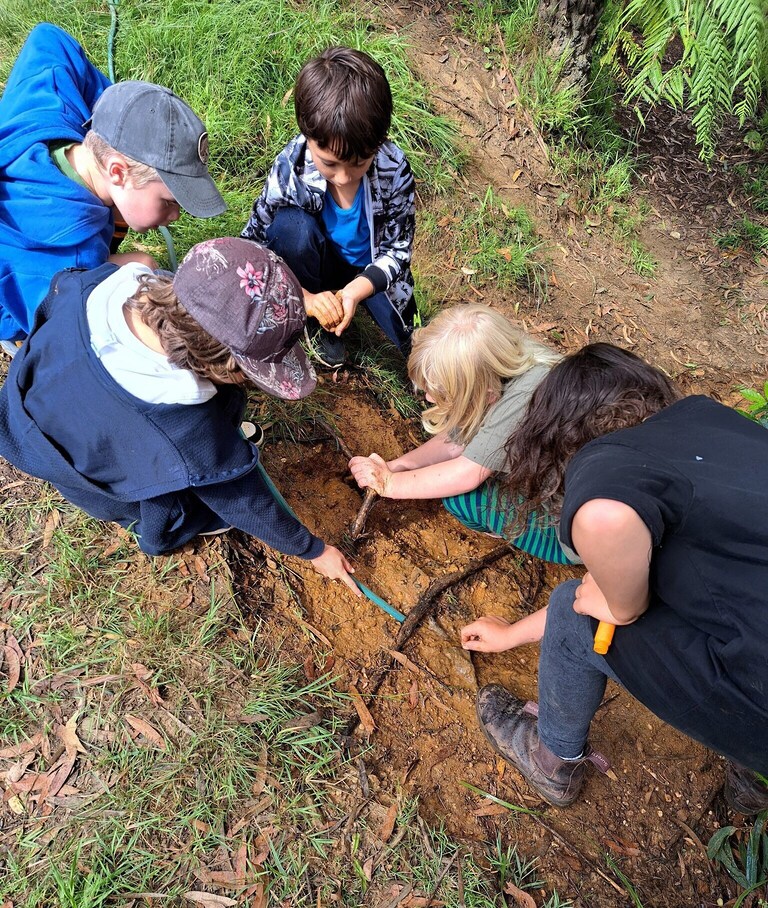 Children collaborate in the soil, fostering a deep connection to Country and community through hands-on outdoor discovery.