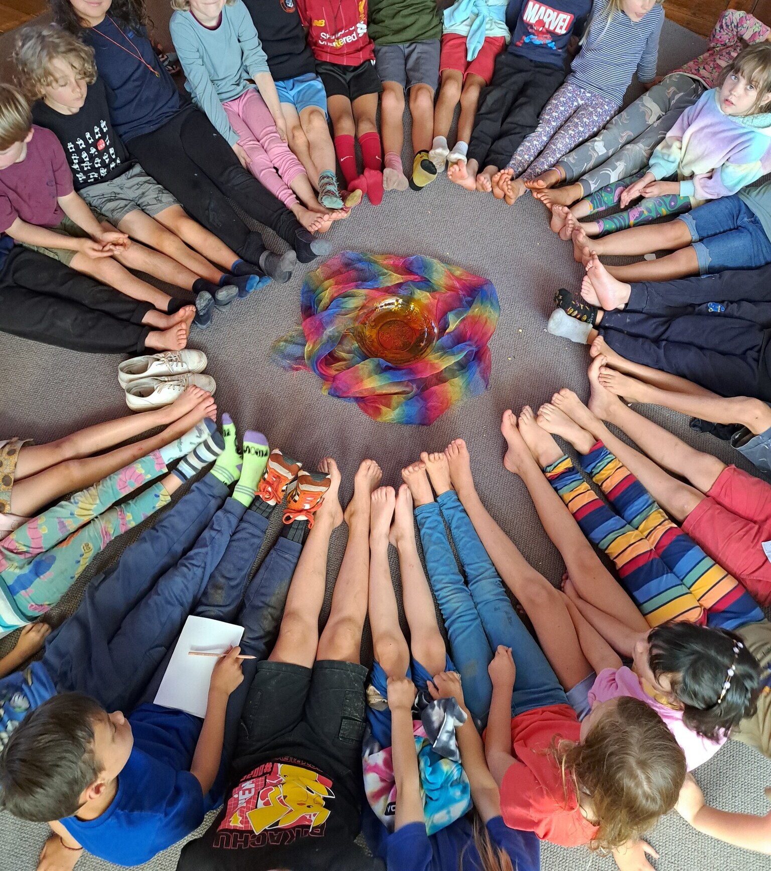 Children gather in a unified circle around a colourful centrepiece, celebrating their shared connection and spirit of community.