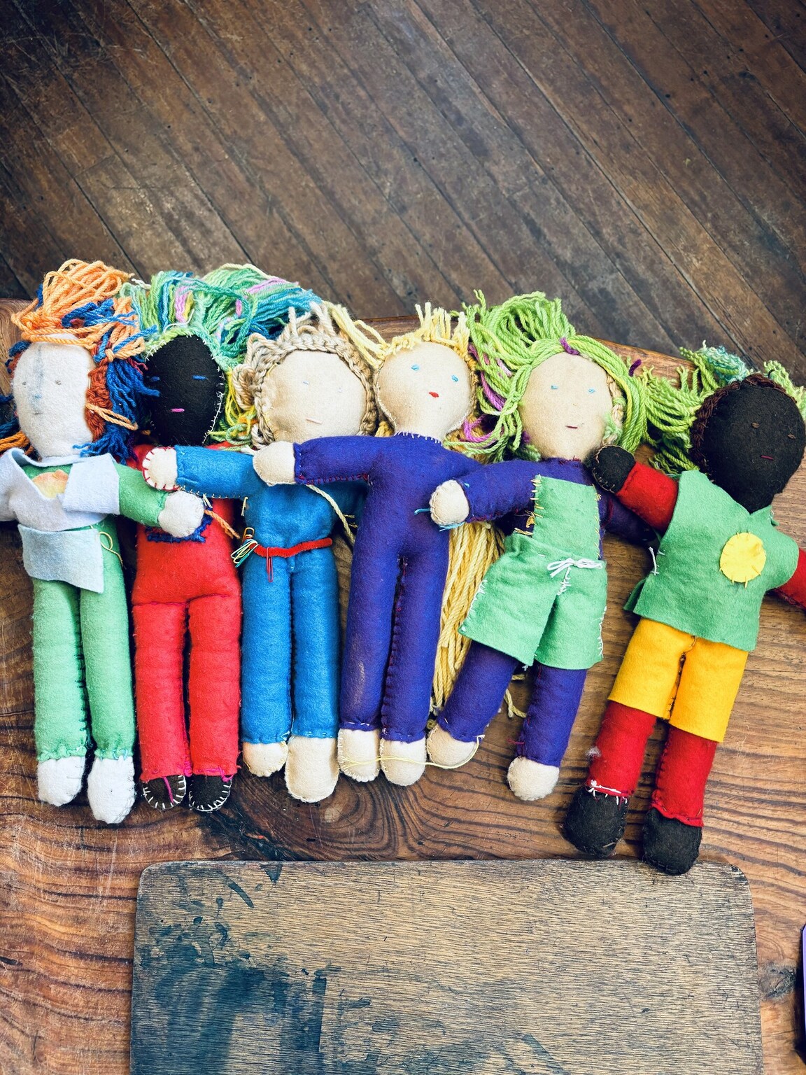 Hand-stitched dolls of diverse colours link together, celebrating a warm community where every child truly belongs.