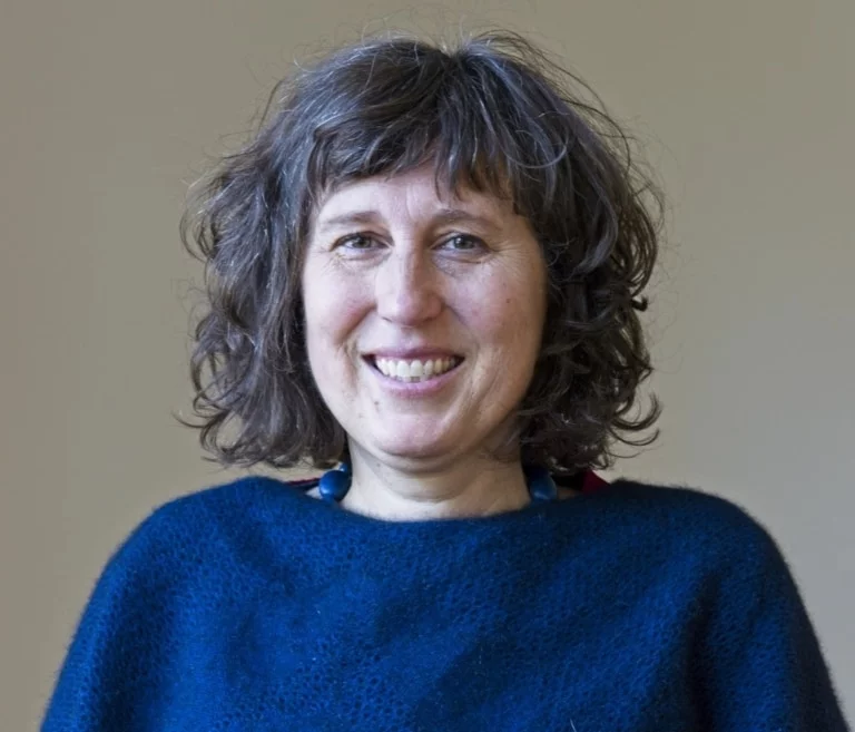 A woman in a blue woollen jumper radiates Kindlehills warmth, heart-centred connection, and compassionate community spirit.