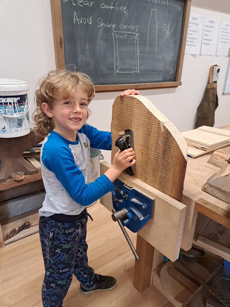 A student shapes timber with a hand plane, connecting head, heart, and hands through purposeful, earth-centred craftsmanship.