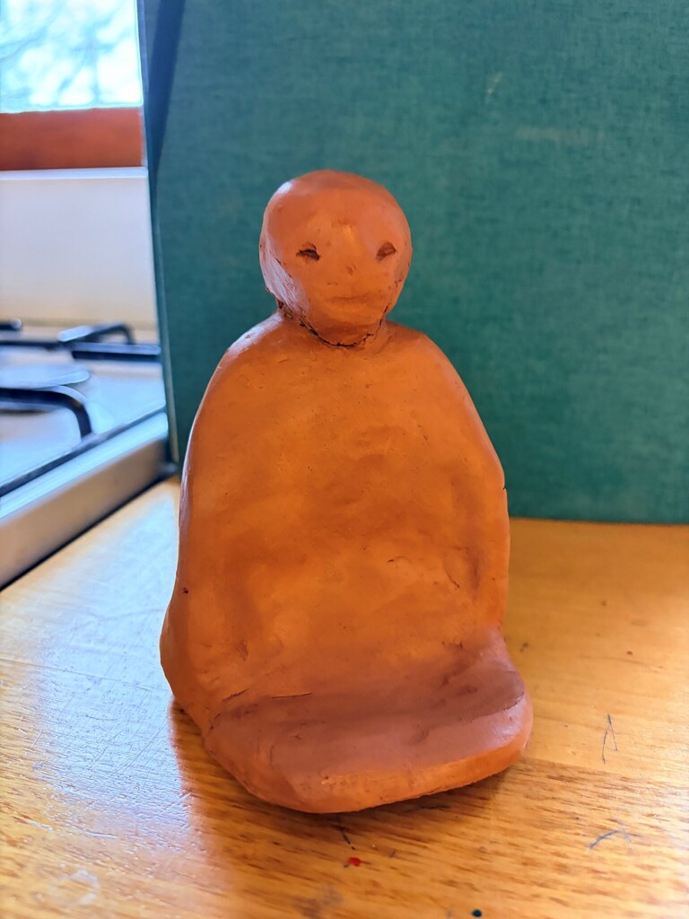 Terracotta figure hand-moulded from the earth, reflecting the creative connection between child, land, and community spirit.