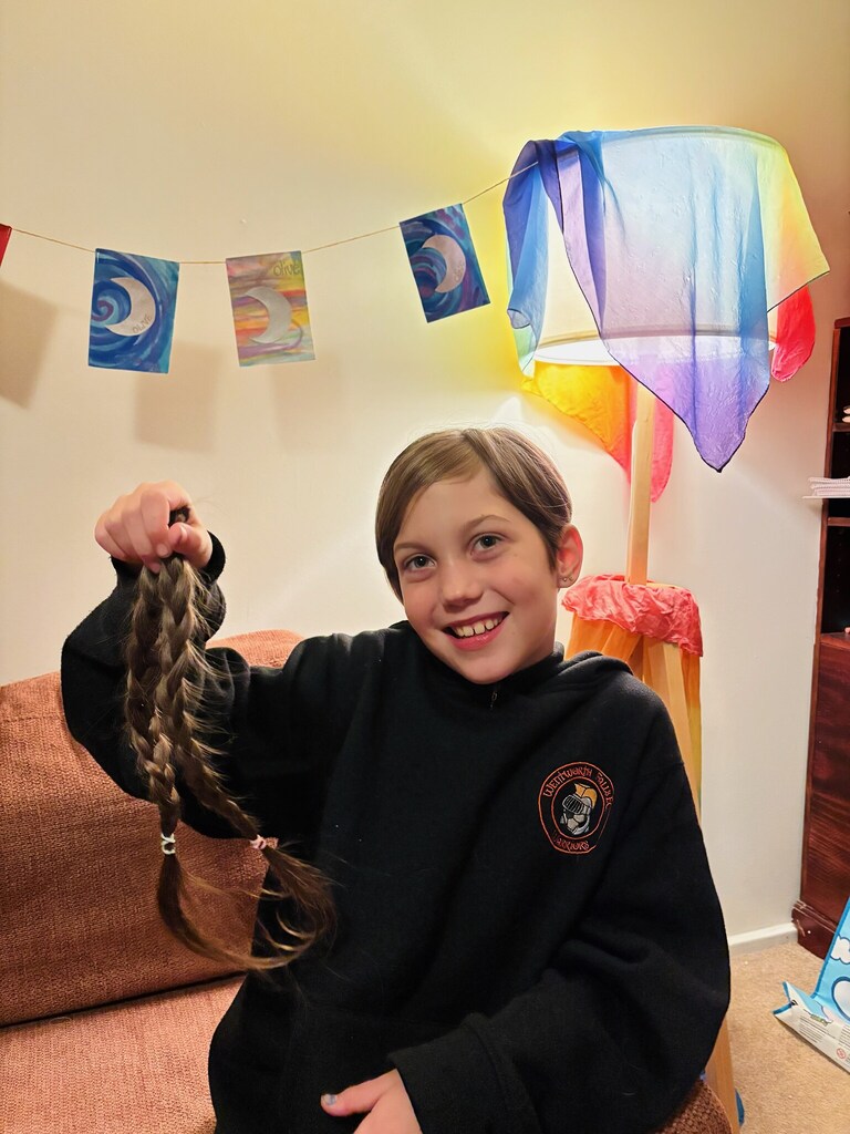 Olive holds her cut ponytails with a smile, transforming a compassionate heart into meaningful action for others.