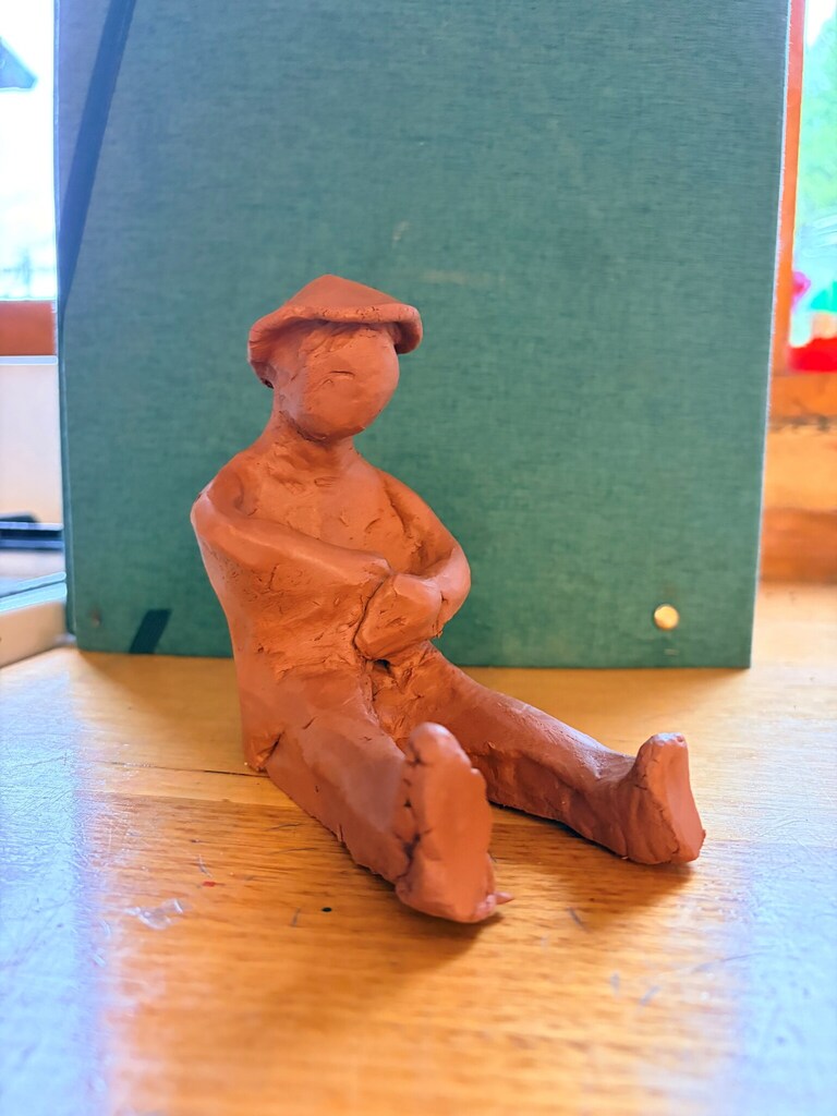 Hand-moulded terracotta figure sits grounded, expressing artistic beauty and a profound sense of belonging to the natural world.