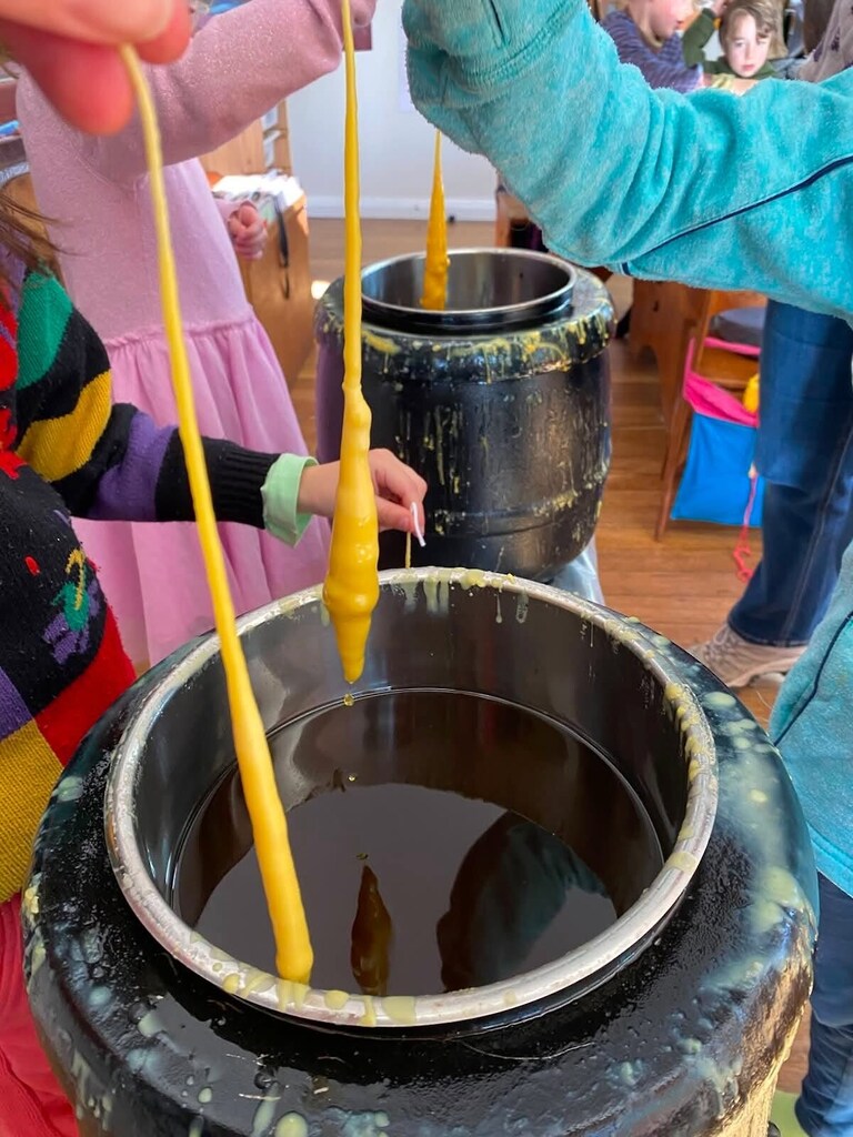 Children hand-dip beeswax candles, honouring seasonal rhythms and the warm spirit of community connection at Kindlehill.