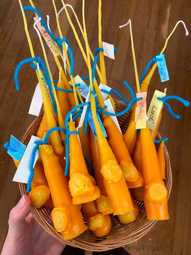 Hand-dipped beeswax candles labelled with names celebrate each childs light within Kindlehills warm community and seasonal rhythms.